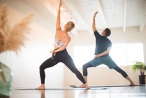 Ein Paar in Reverse-Warrior-Pose beim Yoga. — Stockfoto