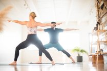 Ein Paar in Krieger 2 posiert beim Yoga. — Stockfoto