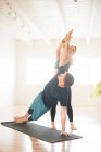 Ein Yogalehrer bietet Seitenplankenhilfe. — Stockfoto