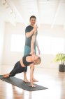 A yoga teacher providing side plank assist. — Stock Photo
