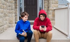 Dois meninos adolescentes sentados e conversando nos degraus da frente de uma casa. — Fotografia de Stock