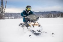 Homem em capacete snowmobiling na colômbia britânica — Fotografia de Stock