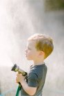 Маленький маленький хлопчик грає з садовим шлангом — стокове фото