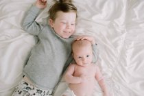 Big brother and his newborn baby sister snuggling on the bed — Stock Photo