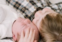 Big brother and his newborn baby sister snuggling on the bed — Stock Photo