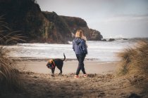 Mujer con un bebé está de pie en la playa californiana - foto de stock