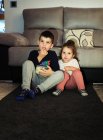 Братья и сёстры смотрят домашнее видео, когда едят попкорн — стоковое фото