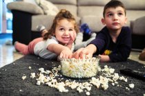 Geschwister schauen sich beim Popcorn-Essen einen Heimatfilm an — Stockfoto