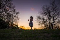Little girl holding flower silohette long hair summer evening sunset — Stock Photo