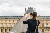 Mulher tirando uma imagem do Louvre em Paris com celular — Fotografia de Stock