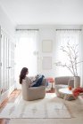 Giovane donna seduta sul divano e libro di lettura — Foto stock