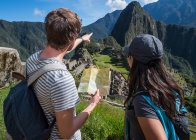 Couple at Inca ruins looking at folding map, Machu Picchu, Peru — Stock Photo