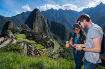 Casal em ruínas incas olhando para mapa dobrável, Machu Picchu, Peru — Fotografia de Stock