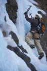 Jovem escalando cascata congelada na Islândia — Fotografia de Stock