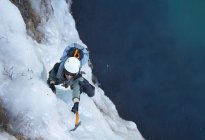 Jovem escalando cascata congelada na Islândia — Fotografia de Stock