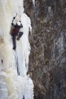 Junger Mann besteigt gefrorenen Wasserfall in Island — Stockfoto