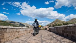 Conducción de motos sobre un puente del río Urubamba, Cusco, Perú - foto de stock