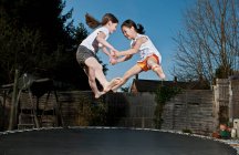 Two young girls jumping on trampoline in Woking - England — Stock Photo