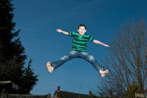 Chico saltando en trampolín en Woking - Inglaterra - foto de stock