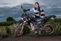 Frau posiert hinter ihrem Supermoto-Motorrad auf Feldweg — Stockfoto