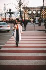 Menina adolescente pensativo em roupas quentes cruzando estrada na cidade no inverno — Fotografia de Stock