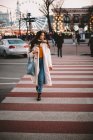 Задумчивая девочка-подросток в теплой одежде переходит дорогу в городе зимой — стоковое фото
