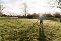 Rückansicht eines kleinen Jungen, der auf der Wiese rennt — Stockfoto