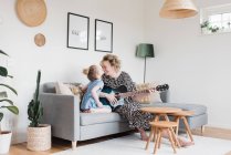 Mutter und Tochter saßen zu Hause lachend zusammen und spielten Gitarre — Stockfoto