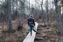 Frau spaziert mit Rucksack und Gitarre durch Wald — Stockfoto