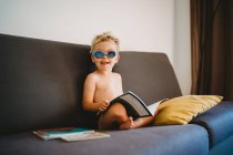 Männliches Kind liest oben ohne mit Brille und streckt die Zunge heraus — Stockfoto