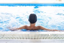 Jovem adolescente do sexo masculino com boné branco relaxante em uma piscina no spa — Fotografia de Stock