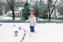 Little kid clearing the snow off the solar lamps in her yard. — Stock Photo