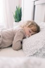 Uma criança dormindo na cama de seus pais com uma chupeta. — Fotografia de Stock