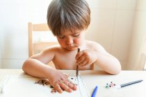 Немає сорочки маленький хлопчик сидить на столі малюючи вдома — стокове фото