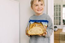 Carino piccolo bambino in possesso di una pagnotta fatta in casa di pane di pasta madre. — Foto stock