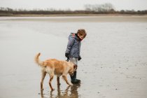 Cute boy and golden retriever labrador dog on beach — Stock Photo