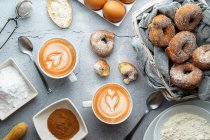 Caffè con latte art e piccole ciambelle con zucchero e cannella e ingredienti. Ciambelle dessert — Foto stock