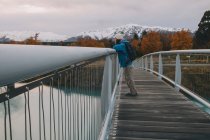 Frau blickt von Brücke mit Bergen im Hintergrund auf den Tekapo-See. — Stockfoto