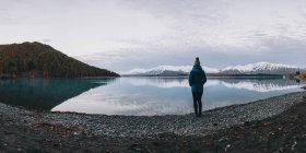 Une jeune femme se tient devant le lac Tekapo et les Alpes du Sud — Photo de stock