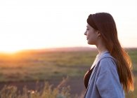 Jolie fille brune au coucher du soleil dans la nature — Photo de stock