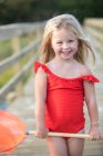 Bambina in costume da bagno rosso sul ponte con rete da pesca rossa — Foto stock