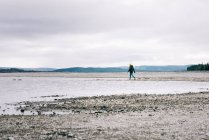 Hombre caminando solo por el agua y las montañas en el norte de Suecia - foto de stock