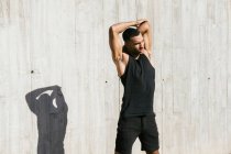 Afrikanisch-amerikanischer Athlet dehnt sich gegen Betonwand — Stockfoto