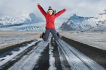 Mujer saltando en medio de una carretera en Islandia - foto de stock