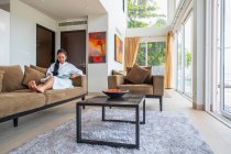 Schöne Frau liest im Wohnzimmer einer Luxusvilla in Phuket — Stockfoto