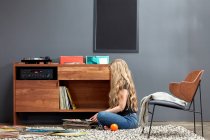 Woman sorting through vinyl records by custom stereo cabinet — Stock Photo