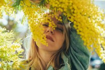Портрет блондинки з жовтою рослиною Мімоза навесні . — стокове фото