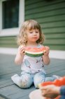Маленькая девочка ест арбуз на открытом воздухе — стоковое фото