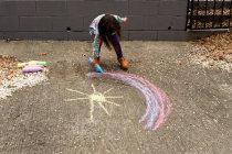 Little girl drawing rainbow with chalk — Stock Photo