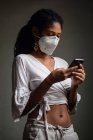 Женщина в маске с помощью смартфона — стоковое фото